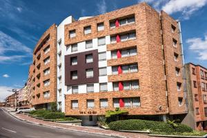 a brick building with red windows on a street at Viaggio Urbano Business in Bogotá