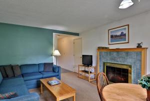 ein Wohnzimmer mit einem blauen Sofa und einem Kamin in der Unterkunft Cedarbrook Queen Suite 103 in Killington