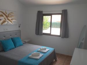 Un dormitorio con una cama con almohadas azules y una ventana en Santa Barbara by Placida Mar en Playa del Inglés