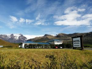 a motel sign in front of a building with mountains in the background at Hotel Skaftafell in Skaftafell