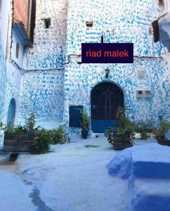a building with a blue door and a sign that reads had market at casa malek in Chefchaouene