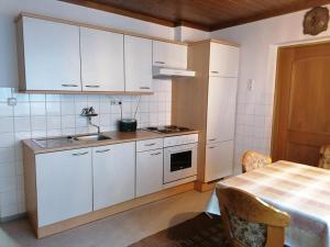 a kitchen with white cabinets and a table with a sink at Hortensia - Appartment - Ferienwohnung - Ferienhaus in Münzkirchen