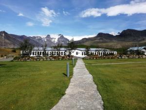 a stone path leading to a white building with mountains in the background at Hotel Skaftafell in Skaftafell