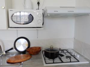 a microwave above a stove with a pot on it at Apartment Studio Halfon in Moorea