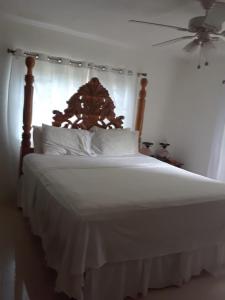 Cama blanca con cabecero de madera y almohadas blancas en Treaysures, en Santa Cruz