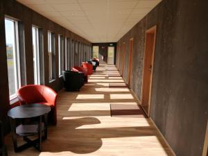 um corredor com cadeiras vermelhas e pisos de madeira e uma fila de janelas em Hotel Skaftafell em Skaftafell
