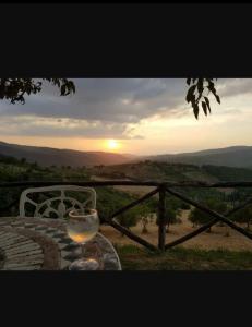 ein Glas Wein auf einem Tisch mit Sonnenuntergang in der Unterkunft Camere e Appartamenti Baldini Romanita in Radda in Chianti
