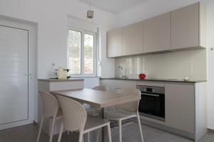 WeCrete Apartments في Dhrapaniás: مطبخ أبيض مع طاولة وكراسي خشبية