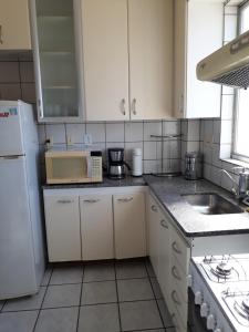a kitchen with a sink and a white refrigerator at Apartamento Uberlândia - BH in Belo Horizonte