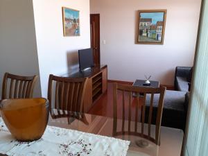 uma sala de estar com uma televisão e uma mesa e cadeiras em Apartamento Uberlândia - BH em Belo Horizonte