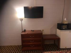 a lamp on a dresser with a television on a wall at Economy Inn in Crossville