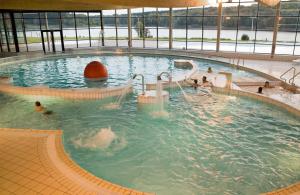 ein großer Pool mit Menschen im Wasser in der Unterkunft Madame Vacances Les Cottages De Valjoly in Eppe-Sauvage