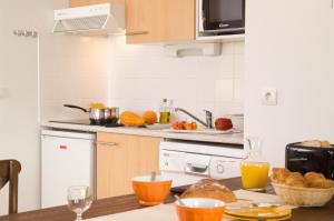 a kitchen with a table with bread and orange juice at Madame Vacances Les Cottages De Valjoly in Eppe-Sauvage