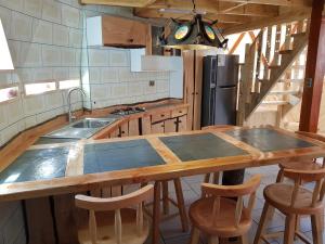 una cocina con una gran mesa de madera y algunos taburetes de bar en Jardín de domos: Pucon, en Pucón