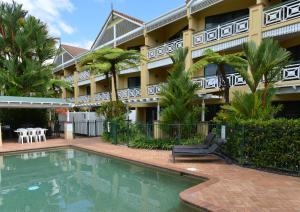 a hotel with a swimming pool in front of a building at Waterfront Terraces in Cairns