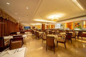 廣州的住宿－嘉逸國際大酒店，一间设有白色桌椅的餐厅和一间酒吧