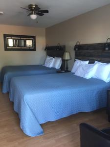 2 Betten in einem Hotelzimmer mit blauer Bettwäsche in der Unterkunft Kacee's Northern Suites in Fort Nelson