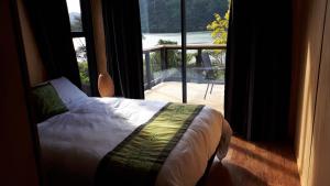 een slaapkamer met een bed en een groot raam bij Marlborough Sounds Accommodation in Havelock
