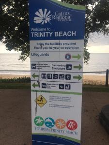 a sign at the beach with the ocean in the background at Casablanca Domes Trinity Beach in Trinity Beach