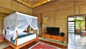 a bedroom with a canopy bed and a television at Chapung Sebali in Ubud