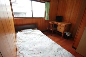 a bedroom with a bed and a desk and a window at Guest House Aman in Amami