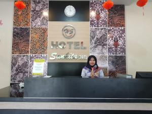 una mujer está parada detrás de un mostrador en un hotel en Hotel Sun Q Ta Guci en Tegal
