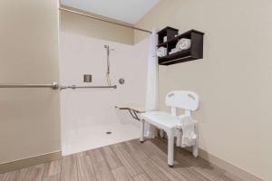 a bathroom with a white chair and a shower at Travelodge by Wyndham Angels Camp CA in Angels Camp +33 photos