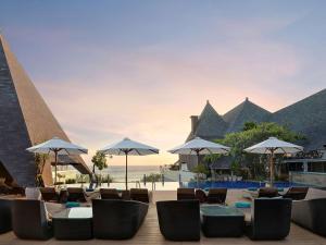 
a patio area with chairs, tables and umbrellas at The Kuta Beach Heritage Hotel - Managed by Accor in Kuta
