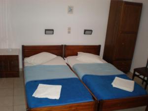 two beds in a bedroom with blue and white sheets at Chrysa in Antiparos