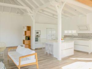 eine weiße Küche mit einem Sofa und einem Tisch in der Unterkunft Villa Ondines in Les Anses-dʼArlets