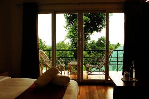 Habitación con cama y vistas a un balcón. en Bellavista Resort Munnar, en Munnar