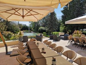 a patio with tables and chairs and an umbrella at Chateau De Rilly - Les Collectionneurs in Rilly-la-Montagne