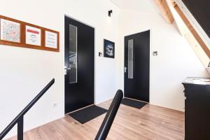 a hallway with two black doors and wooden floors at ROYAAL APPARTEMENT CENTRUM MIDDELBURG in Middelburg
