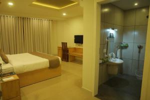a bedroom with a bed and a bathroom with a shower at The Hotel Chettungal in Angamaly