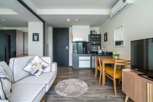 a living room with a couch and a dining room at The Deck Condominium by Lofty in Patong Beach