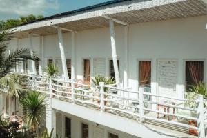 a white building with white railings and palm trees at Gili Amor Boutique Resort in Gili Trawangan