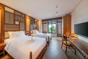 a bedroom with two beds and a desk and a tv at Minh Boutique in Danang