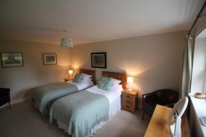 ein Hotelzimmer mit 2 Betten und einem Stuhl in der Unterkunft The Steadings Cottage in Chesters