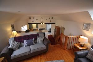 a living room with a couch and a kitchen at The Steadings Cottage in Chesters