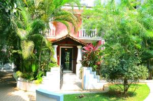 una casa rosa con palmeras delante en Villa Samaara9 Candolim Beach en Candolim