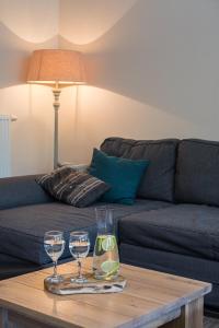uma sala de estar com um sofá e dois copos de vinho numa mesa em ‘t Vaerthuys em Dilsen-Stokkem
