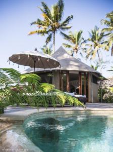 a house with an umbrella and a swimming pool at Sandat Glamping Tents in Ubud