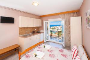 eine Küche und ein Wohnzimmer mit einem Bett und einem Balkon in der Unterkunft Athanasia Rooms in Mariaí