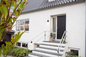 uma casa branca com uma porta preta e escadas em Brøndums Bed & Breakfast em Hjørring
