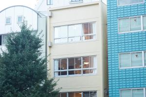 a tall building with a blue tile facade at No Service Hotel in Tokyo