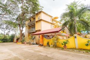 un edificio giallo con palme di fronte di RedDoorz Premium @ Gabinete Road Palawan a Città di Puerto Princesa