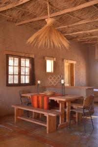 um quarto com uma mesa, bancos e janelas em Casas Valle De La Luna em San Pedro de Atacama