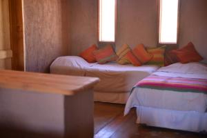 a small room with two beds and two windows at Casas Valle De La Luna in San Pedro de Atacama