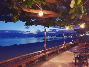 een patio met een tafel en stoelen en uitzicht op de oceaan bij Playa Papagayo Beach Inn in Olongapo