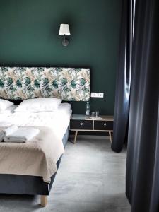 een slaapkamer met een bed en een groene muur bij Willa Moryń in Moryń